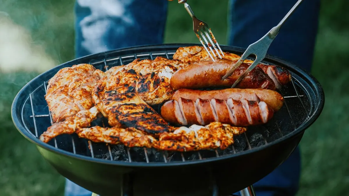 Gedeckter Gartentisch mit Grillwürstchen und Salaten